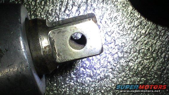 Metal part with a hole, possibly a socket wrench attachment, with textured background