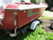 1972 Champion 181 SX - A red boat with a grey stripe is parked on a trailer in a grassy area.