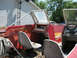 1972 Champion 181 SX - The interior of an old red boat shows two worn bucket seats and a steering wheel, with a building in the background.