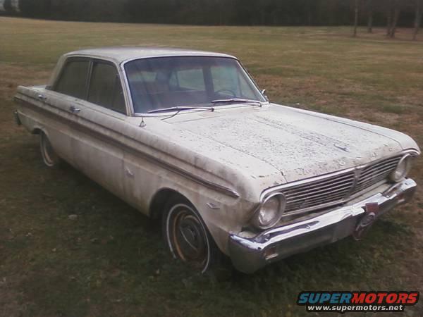 White sedan parked on grass, front quarter view. Chrome grille and bumper are visible