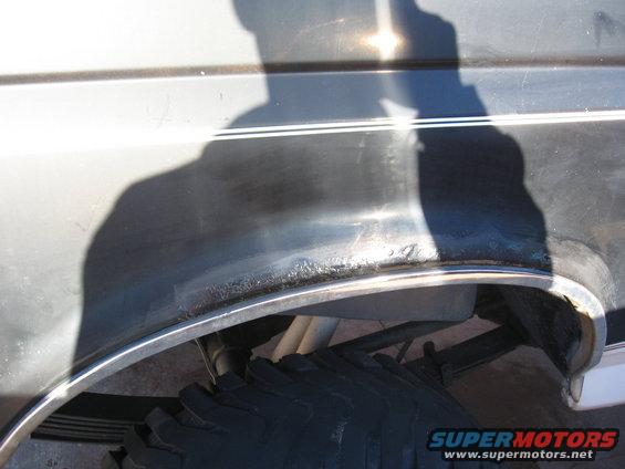1992 Ford Bronco rear fender wheel well with chrome trim and visible suspension components