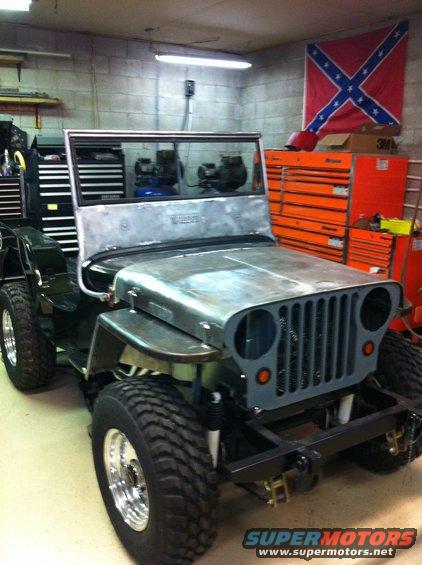 Jeep CJ-3A body in garage, unfinished, with toolbox and Confederate flag in background