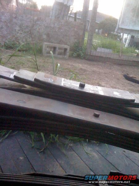 Stack of metal leaf springs on a wooden surface