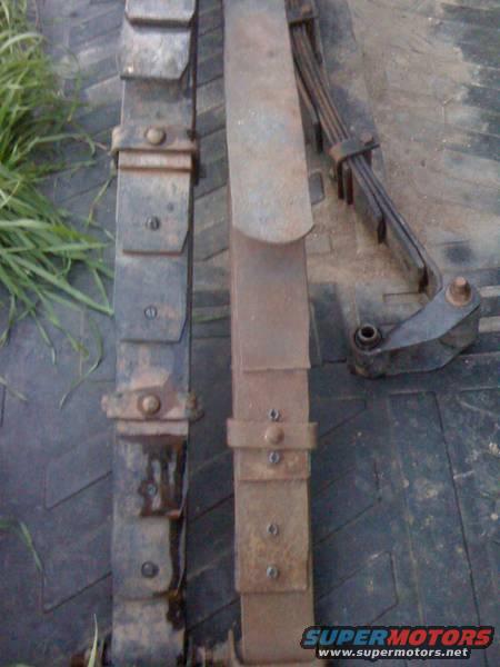 two old leaf springs, one is rusty and brown, the other is dark and dirty