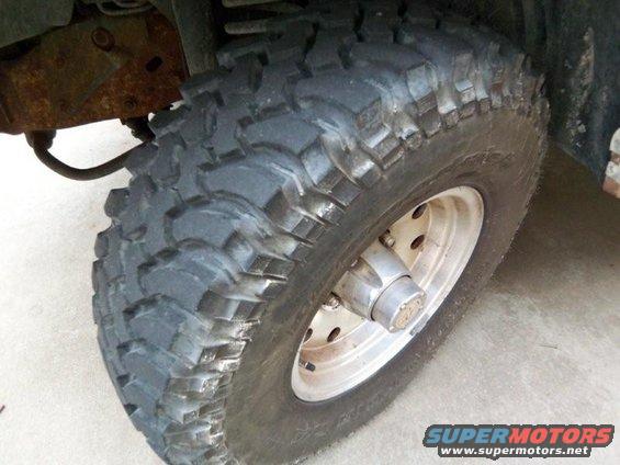 Off-road tire on silver wheel with visible rust on suspension components