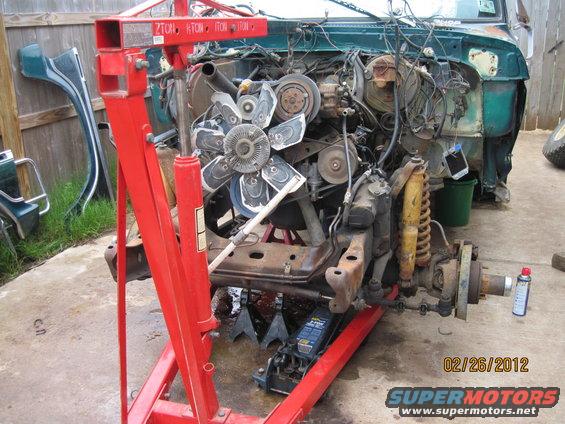 Disassembled truck engine and front suspension on an engine hoist. Date stamp reads 02/26/2012