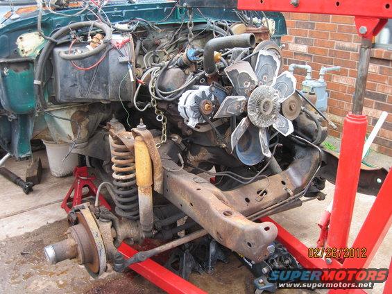 engine and front suspension removed from vehicle, supported by engine hoist and jack stands