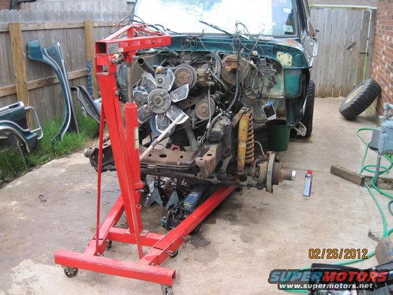 Engine hoist lifting disassembled vehicle, green body, engine exposed