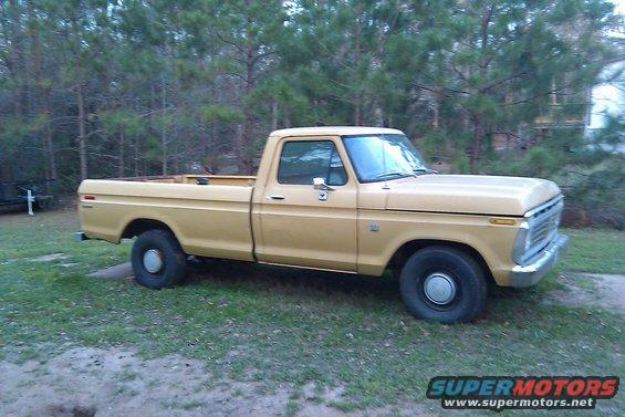 1973 Ford F-100 pickup truck parked on grass with trees in background