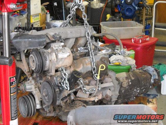 Engine and transmission assembly being hoisted by chains in a garage