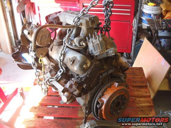 Engine with chains, on wooden pallets, with red tool chest in background