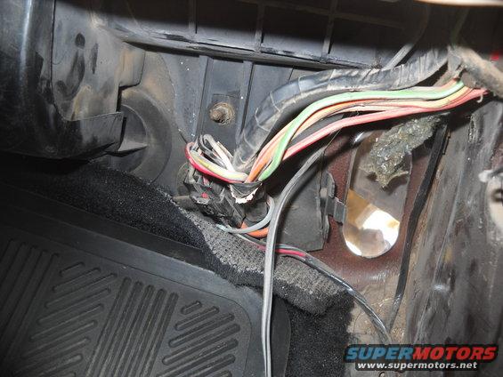Close-up of a vehicle's interior wiring harness and floor mat
