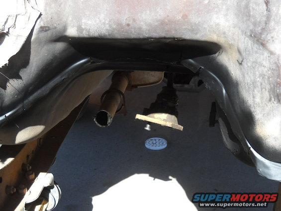 Underside view of vehicle exhaust pipe and suspension components. Supermotors.net logo visible