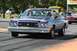 1973 Ford Ranchero - A blue coupe utility vehicle with two occupants drives down a track, with another vehicle visible behind it.