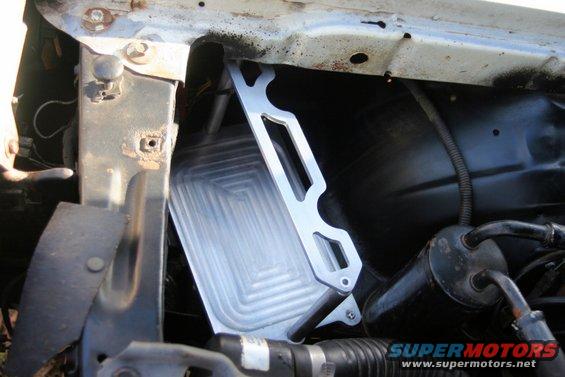 Aluminum battery tray mounted to radiator support structure. Some rust visible on metal