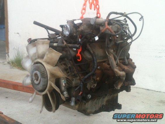 Engine assembly with fan and hoses, suspended by orange chains