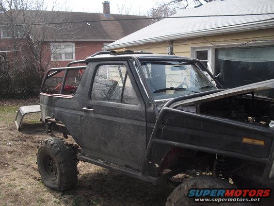 Black Ford Bronco with roll cage, lifted suspension, and off-road tires, hood open