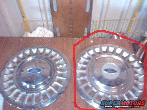 Two Ford hubcaps on a wooden surface