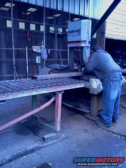 Man in jeans and sweatshirt using a Marvel brand metal cutting saw in a workshop