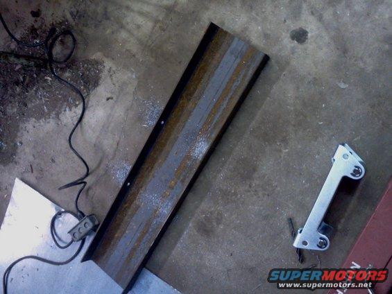 Metal winch mount with rust and drill shavings on concrete floor