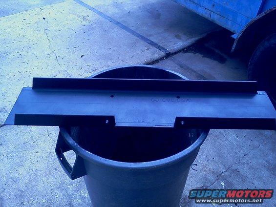 Black metal winch mount part with CVLUSA text, resting on a gray bucket