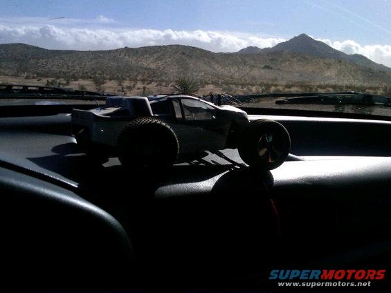toy monster truck on dashboard with desert mountains outside