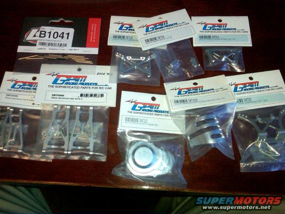 Collection of GPM Racing Products for RC cars, including suspension arms and shock covers