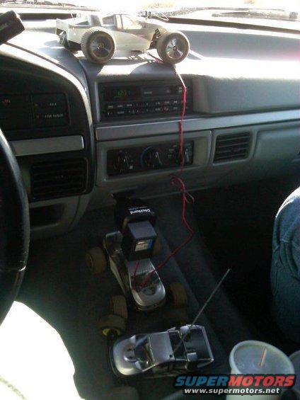 Dashboard interior with two remote control cars, one on top of the other, and a cup holder