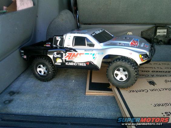 RC race truck with AM/SOY and Kumho Tires decals, sitting in the back of a vehicle