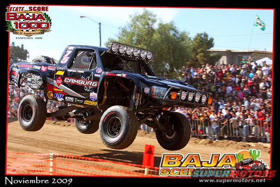 Black off-road truck mid-air, "CAMBURG" visible on side