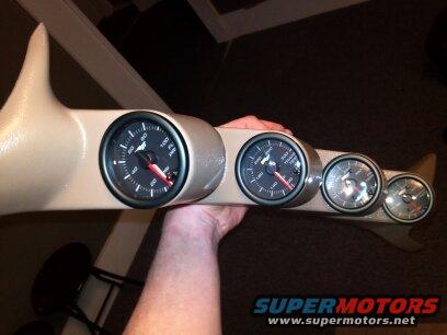 Tan gauge pod with four gauges, held by a hand