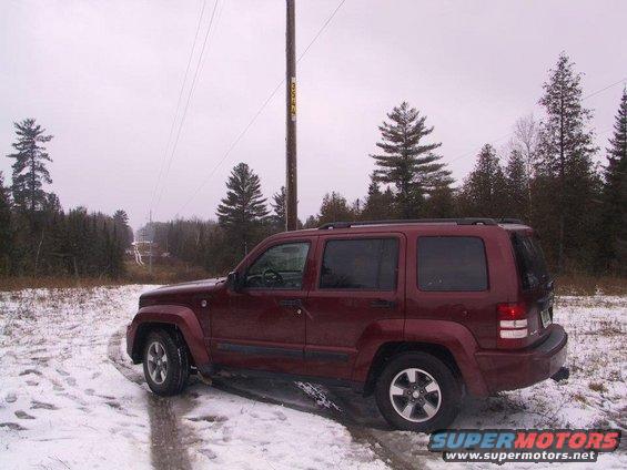 Red Jeep Liberty parked on a snowy road, side view