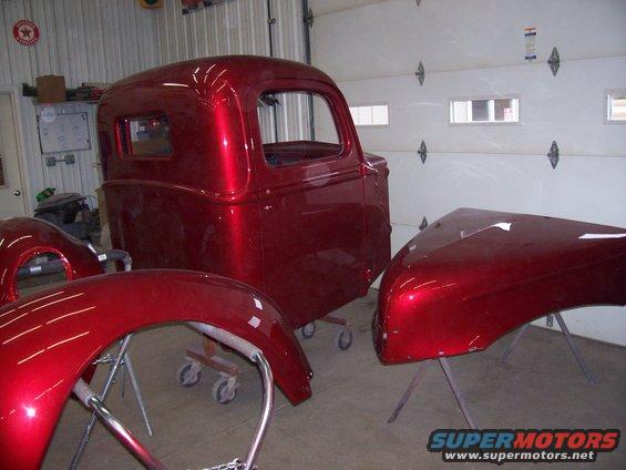 Red metallic classic truck cab and fenders on stands in a garage