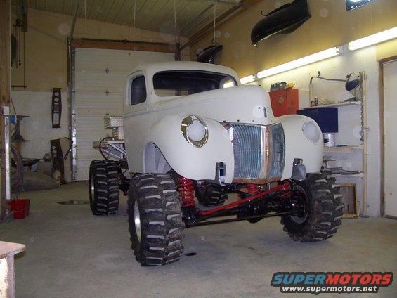 White pickup truck with oversized off-road tires and custom suspension in a garage