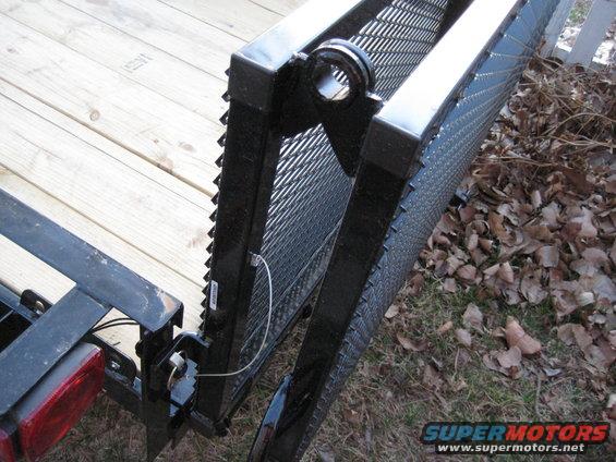 Trailer ramp with black metal grating and wooden deck, close-up view