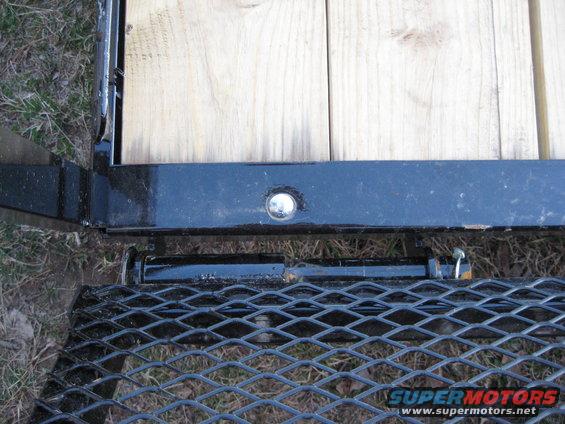 Close-up of a trailer ramp latch mechanism and wooden deck