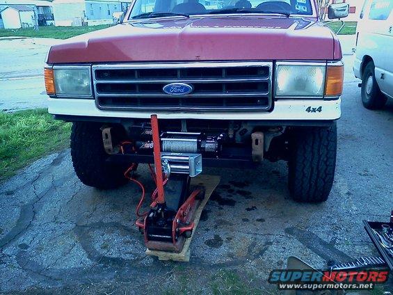 1989 Ford Bronco front end with a winch mounted below the bumper and a jack under the frame