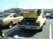 1995 Ford Crown Victoria - A yellow 1970 Ford Mustang Mach 1 is parked next to a gold classic car, both with hoods or trunks open.