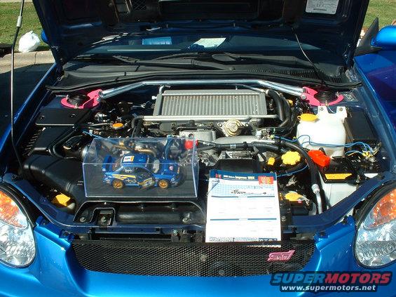 Blue Subaru WRX STI engine bay with model car and information sheet