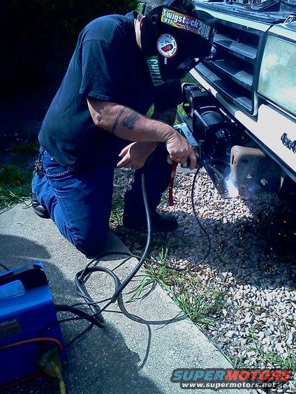Man welding a winch mount on the front of a 1989 Ford Bronco