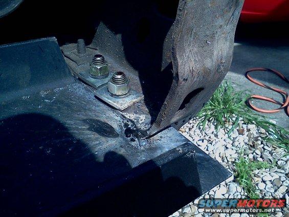 Bolts and nuts securing a metal bracket to a larger metal component, possibly part of a winch mount