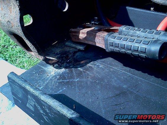 Winch mount with rusty metal and black rubber grips, on a dark surface
