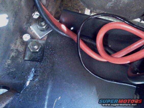 Close-up of red and black battery cables connected to mounting hardware with bolts