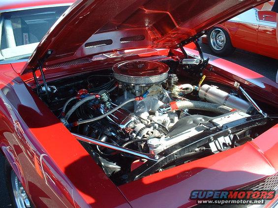 Red car engine bay with chrome air cleaner and visible hoses