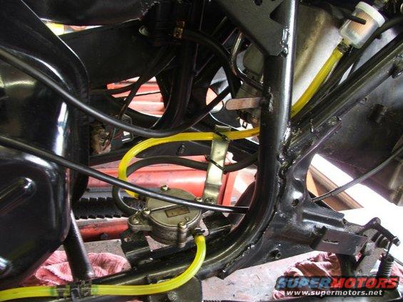Close-up of a motorcycle's fuel pump and yellow fuel lines connected to the carburetor