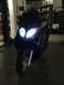 2008 Yamaha Zuma - A dark blue scooter is parked in a garage with its headlights on.