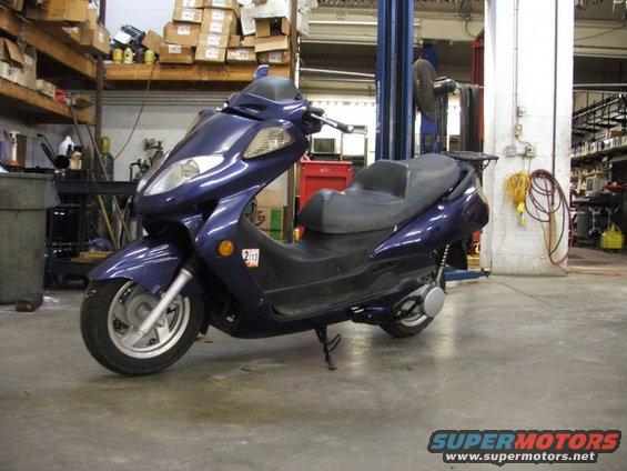 Dark blue scooter side view with a sticker showing '213'