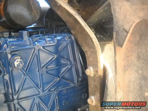 Close-up of a blue engine component with visible part numbers and mounting bolts