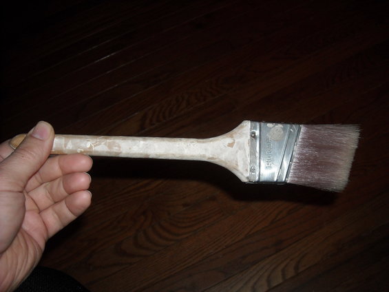 Paint brush held in hand, showing bristles and handle