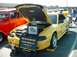 1995 Ford Crown Victoria - A yellow 1998 Ford Mustang convertible is displayed with its hood open, a skeleton and a sign listing owners and custom parts.